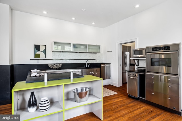 kitchen featuring tasteful backsplash, appliances with stainless steel finishes, dark wood-type flooring, and sink