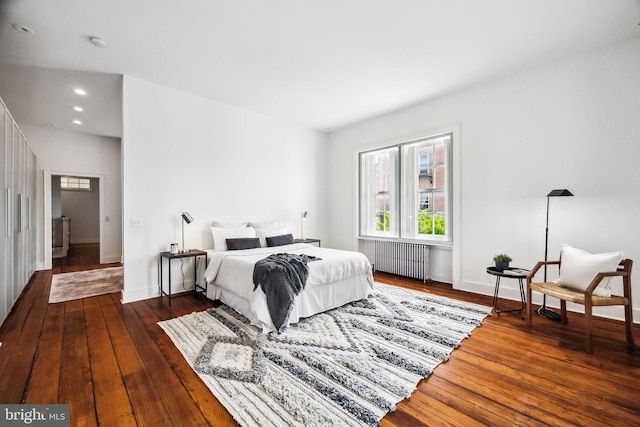 bedroom with dark hardwood / wood-style flooring and radiator heating unit