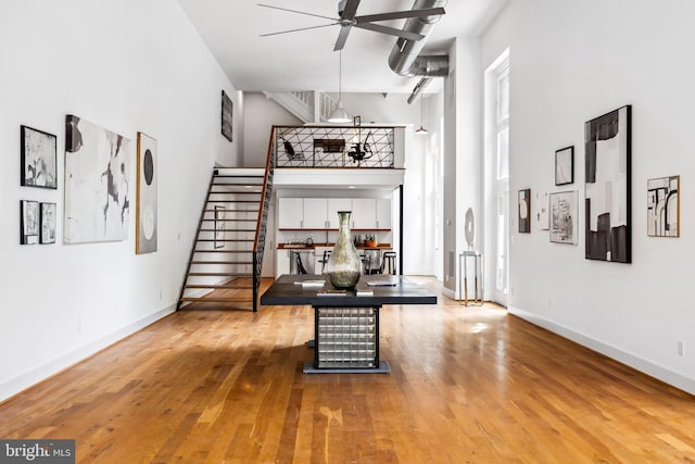 interior space with a high ceiling, ceiling fan, and light wood-type flooring