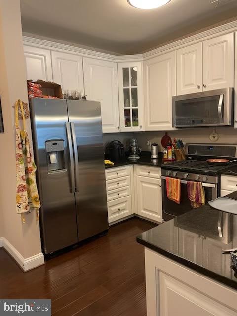 kitchen with white cabinets, dark hardwood / wood-style floors, and appliances with stainless steel finishes