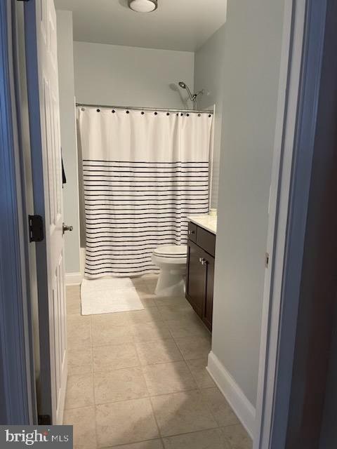 bathroom featuring toilet, vanity, tile patterned floors, and a shower with shower curtain