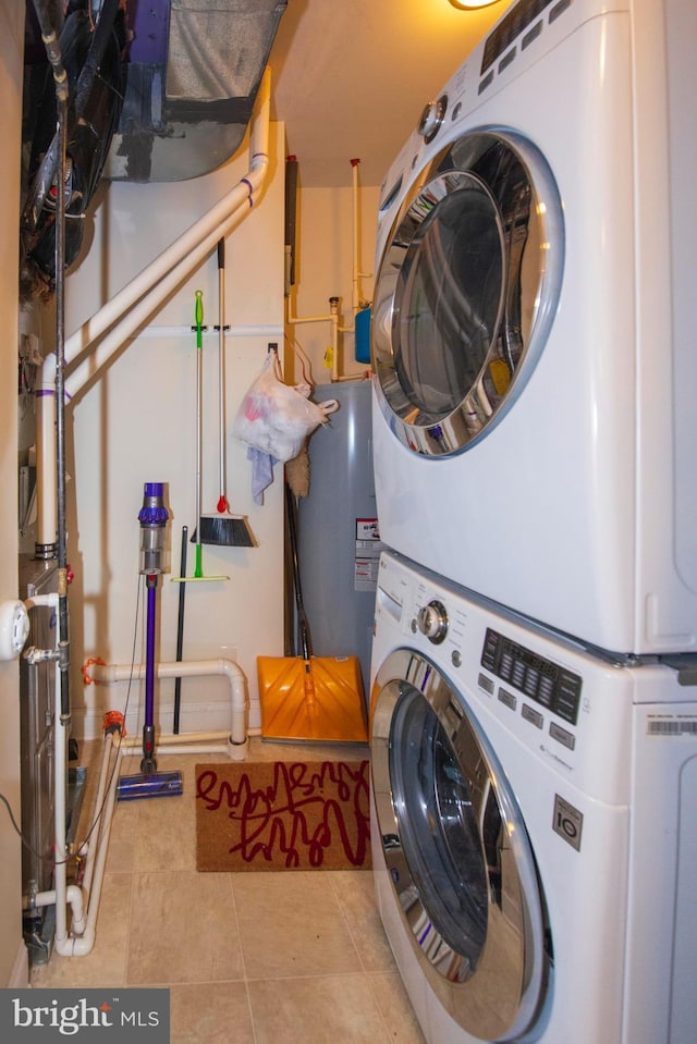 laundry room featuring water heater, light tile patterned floors, and stacked washing maching and dryer