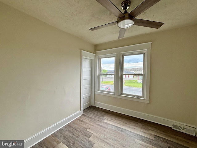 empty room with ceiling fan, light hardwood / wood-style floors, and a textured ceiling