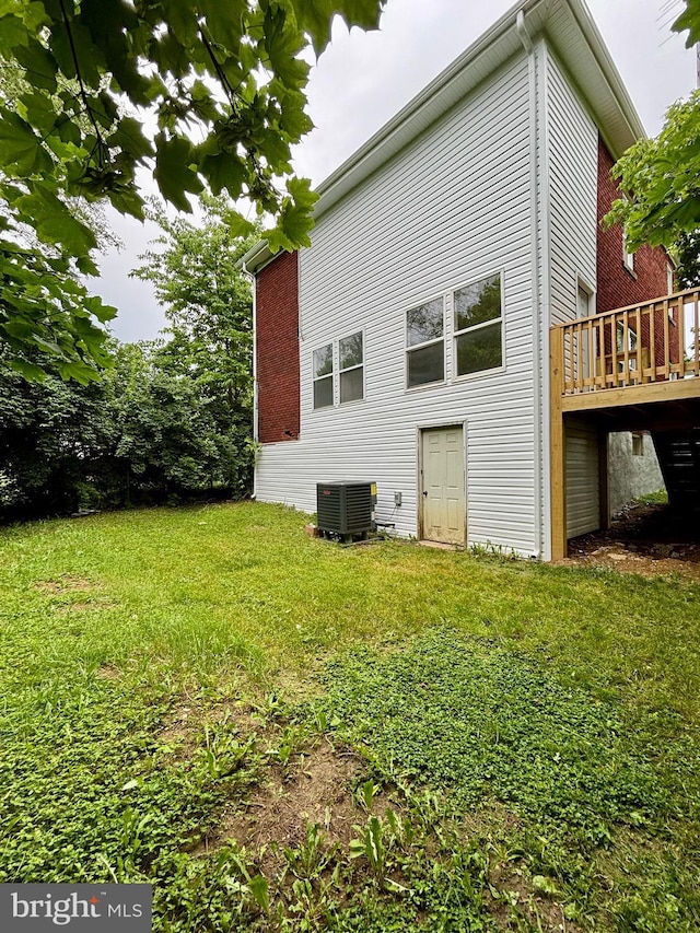 back of house featuring a yard, a wooden deck, and central air condition unit