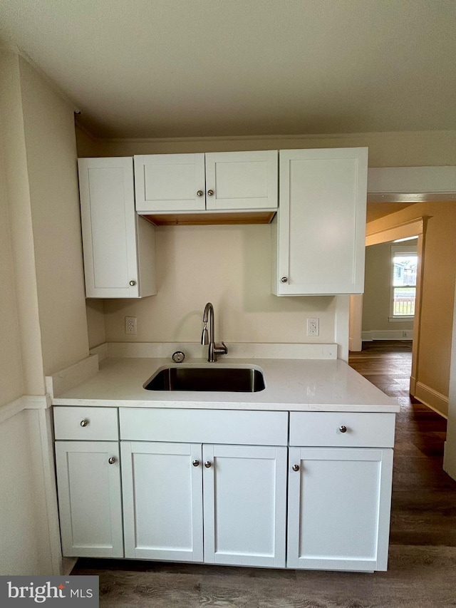 kitchen with dark hardwood / wood-style flooring, white cabinetry, and sink