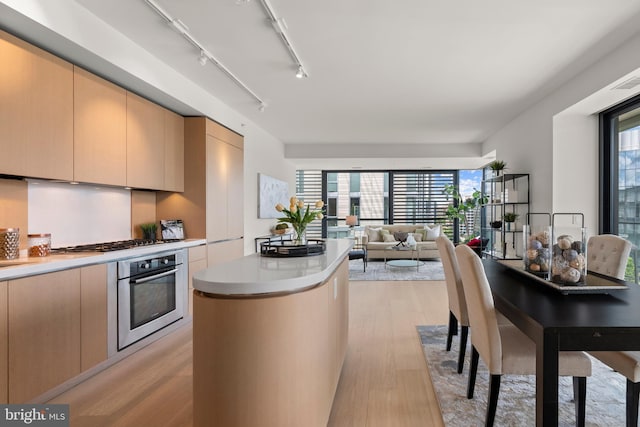 kitchen with stainless steel appliances, a kitchen island, light brown cabinets, and light hardwood / wood-style floors