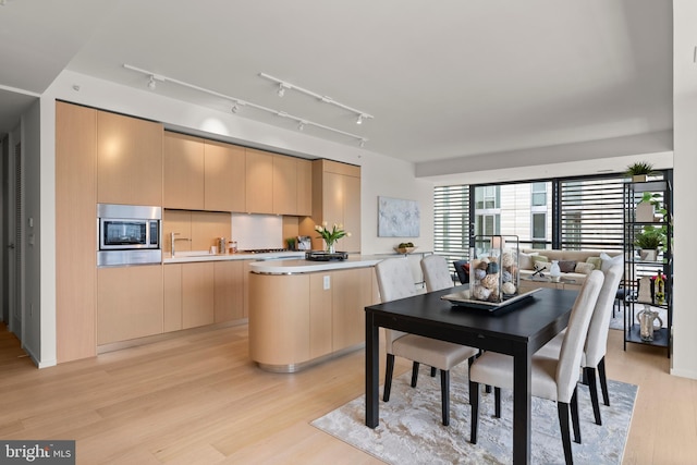 kitchen featuring light brown cabinets, stainless steel microwave, light hardwood / wood-style floors, and kitchen peninsula