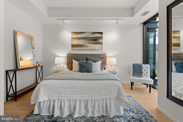 bedroom with multiple windows, track lighting, and light wood-type flooring