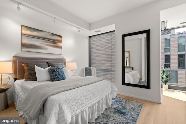 bedroom featuring rail lighting and light wood-type flooring