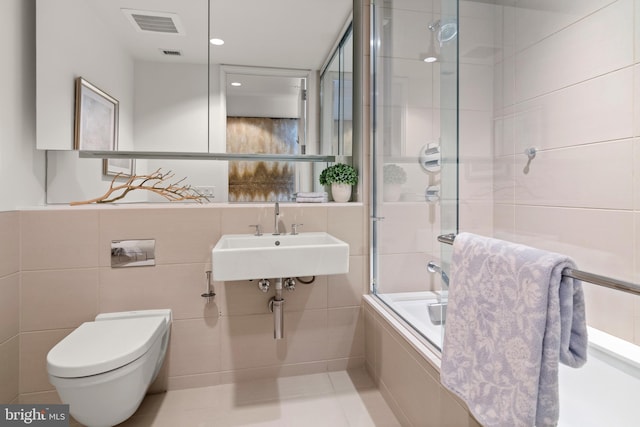 full bathroom featuring enclosed tub / shower combo, sink, tile walls, and toilet