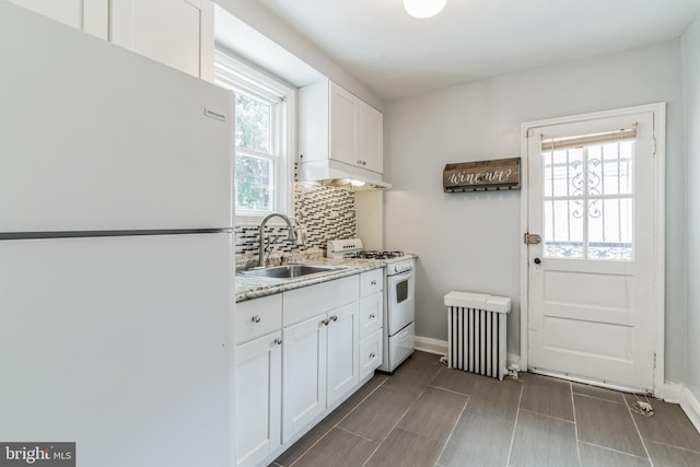 kitchen with white cabinets, white appliances, backsplash, radiator, and sink