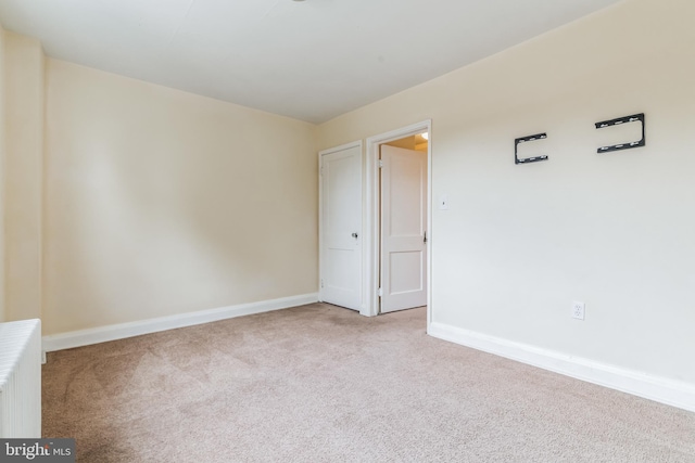 empty room featuring carpet and radiator heating unit