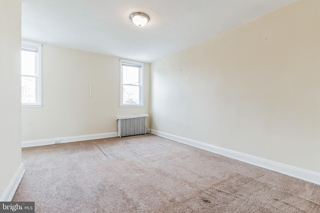 unfurnished room with plenty of natural light, carpet flooring, and radiator heating unit