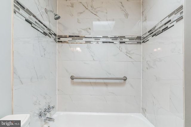 bathroom featuring tiled shower / bath combo and toilet