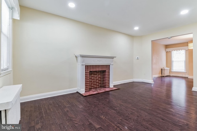 unfurnished living room with a brick fireplace and dark hardwood / wood-style floors