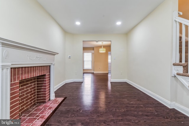 unfurnished living room featuring dark hardwood / wood-style flooring and a brick fireplace