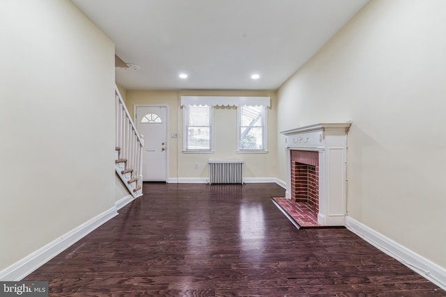 entrance foyer featuring dark hardwood / wood-style flooring, a brick fireplace, and radiator heating unit