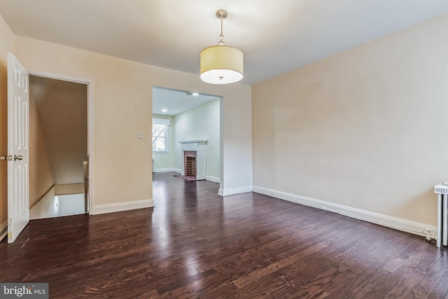 spare room featuring dark hardwood / wood-style flooring and a fireplace