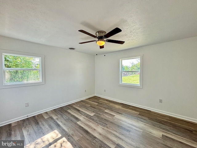 empty room with ceiling fan, a healthy amount of sunlight, wood-type flooring, and a textured ceiling