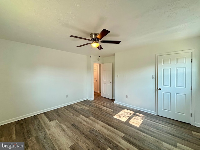 unfurnished bedroom featuring a textured ceiling, ceiling fan, and dark wood-type flooring