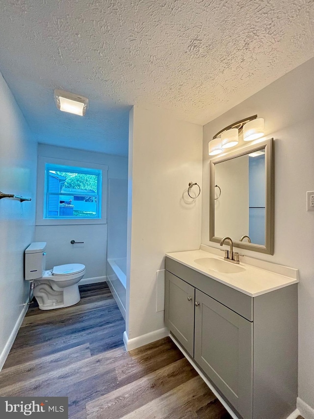 bathroom featuring hardwood / wood-style flooring, vanity, toilet, and a textured ceiling