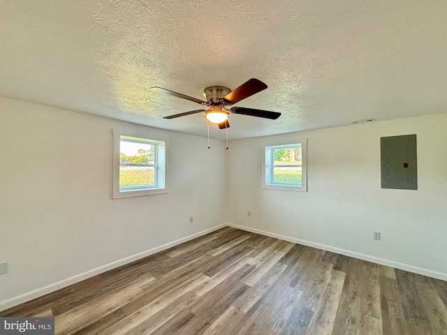 unfurnished room with electric panel, plenty of natural light, and hardwood / wood-style floors