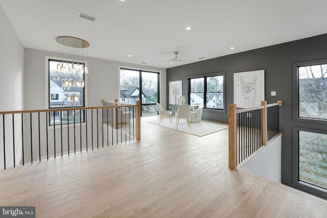 corridor featuring a notable chandelier, light hardwood / wood-style floors, and a wealth of natural light