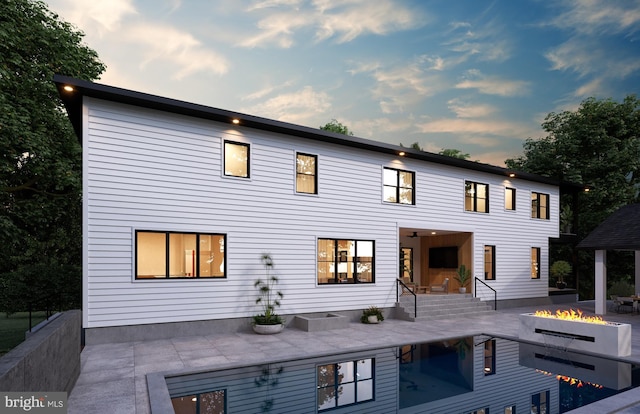 rear view of house with a patio, a pool, and an outdoor fire pit