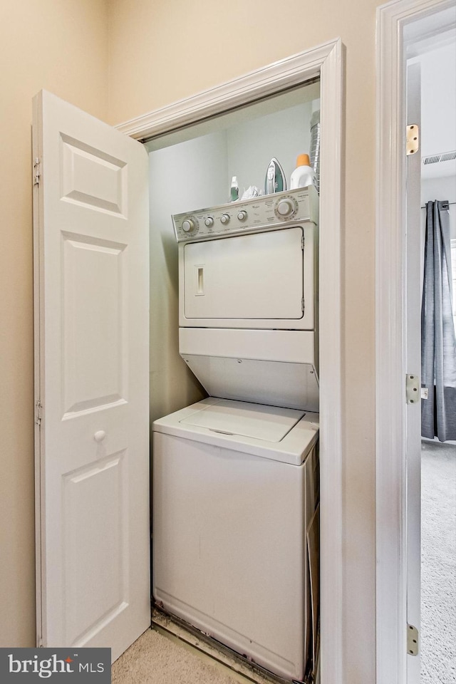 laundry room featuring stacked washer and clothes dryer and light carpet