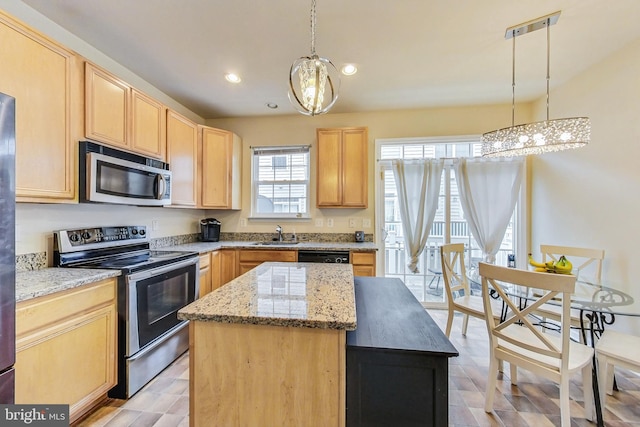 kitchen featuring appliances with stainless steel finishes, a center island, decorative light fixtures, light brown cabinets, and an inviting chandelier