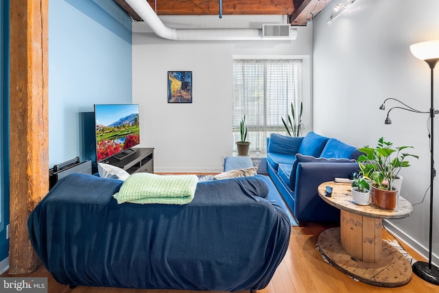 living room featuring beam ceiling, hardwood / wood-style flooring, and track lighting