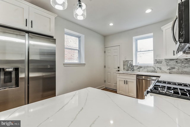 kitchen featuring light stone counters, appliances with stainless steel finishes, backsplash, white cabinetry, and hardwood / wood-style floors