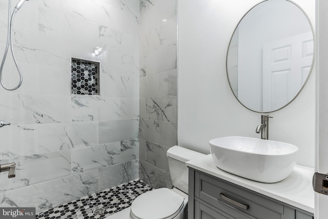 bathroom with toilet, vanity, and a tile shower