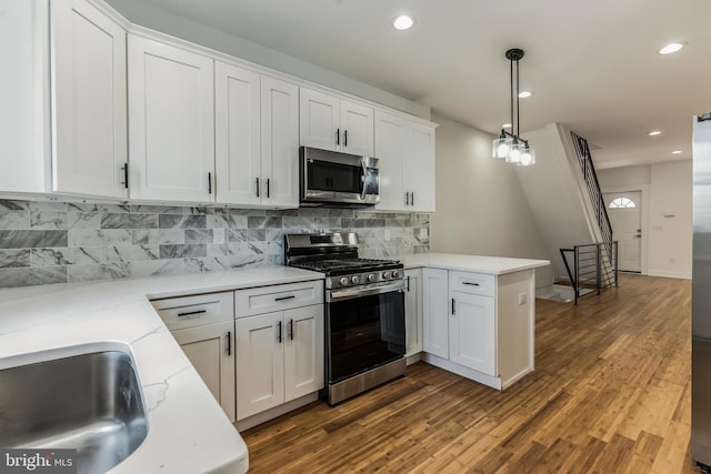 kitchen with decorative light fixtures, dark hardwood / wood-style flooring, white cabinetry, backsplash, and stainless steel appliances