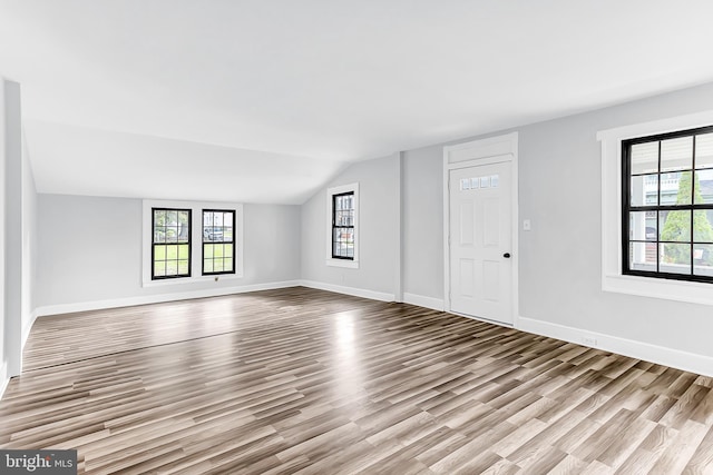 unfurnished living room featuring lofted ceiling, light wood-style floors, and plenty of natural light