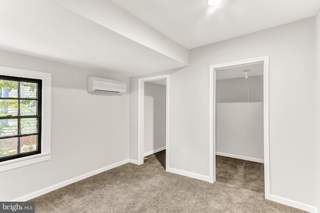 unfurnished bedroom with light carpet, a spacious closet, baseboards, and an AC wall unit