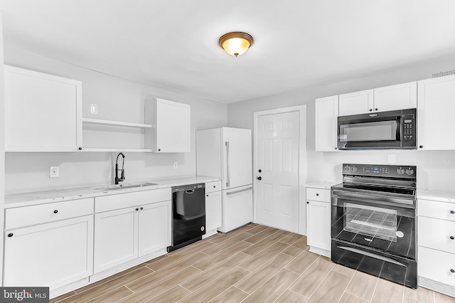 kitchen featuring light stone counters, white cabinets, black appliances, and sink