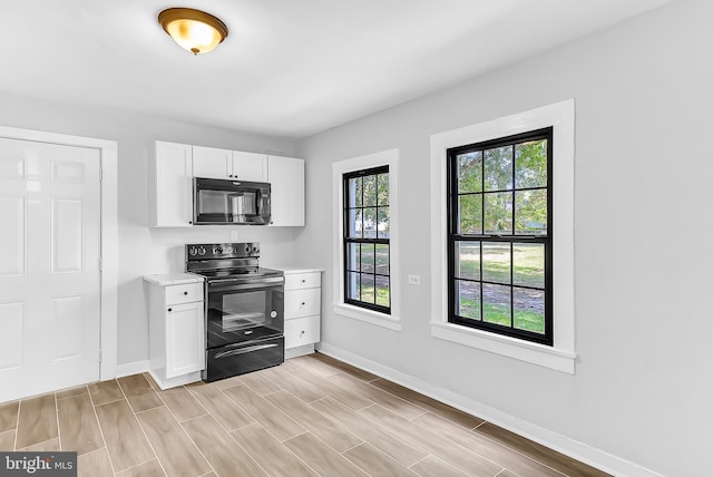 kitchen with black appliances, white cabinets, and a wealth of natural light