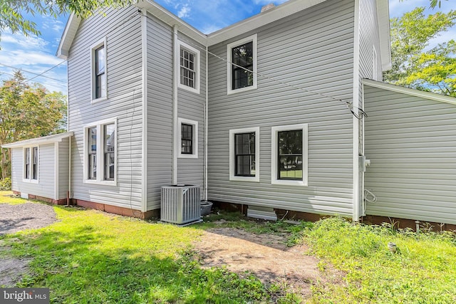 back of property featuring central AC and a yard