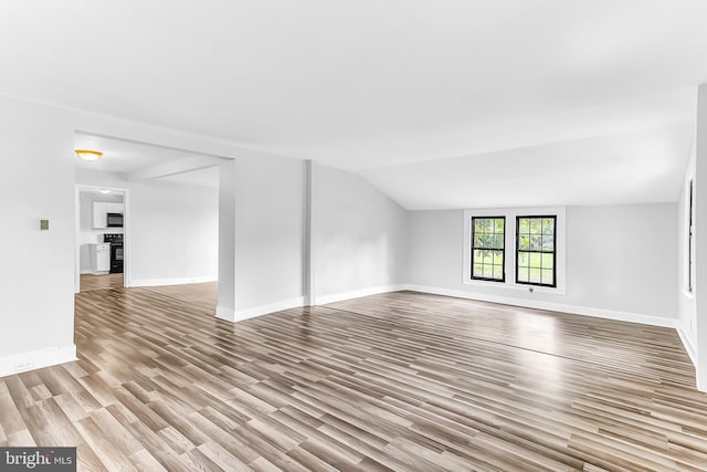 unfurnished living room featuring lofted ceiling, baseboards, and light wood finished floors