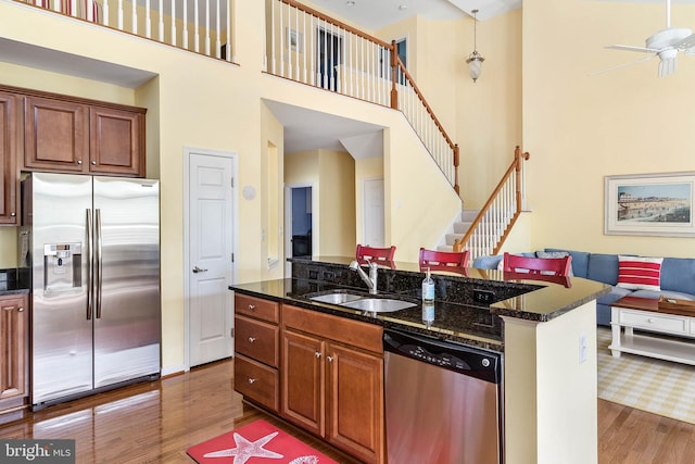 kitchen featuring sink, stainless steel appliances, a towering ceiling, and hardwood / wood-style floors