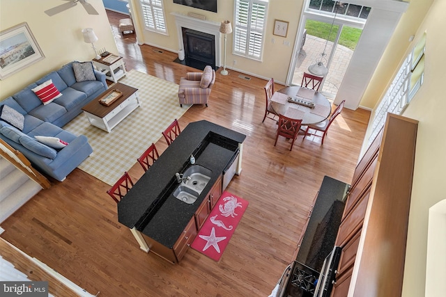 living room with wood-type flooring, ceiling fan, and a towering ceiling