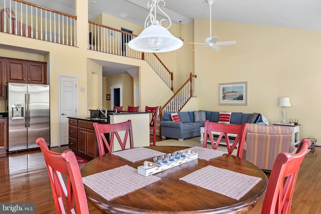 dining room featuring high vaulted ceiling, wood-type flooring, ceiling fan, and sink