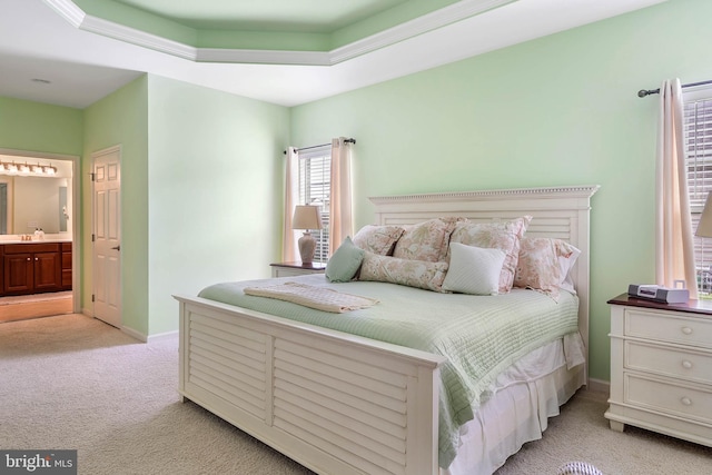 carpeted bedroom featuring ensuite bath, a raised ceiling, and sink