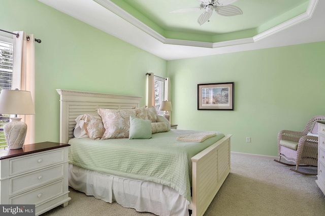 bedroom featuring ornamental molding, light colored carpet, ceiling fan, and a tray ceiling