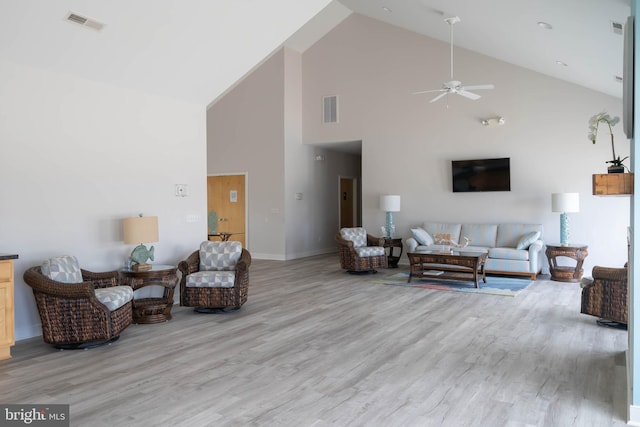 living room with hardwood / wood-style flooring, ceiling fan, and high vaulted ceiling