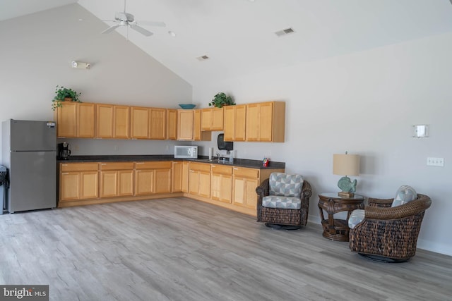 kitchen featuring high vaulted ceiling, white appliances, ceiling fan, light brown cabinetry, and light wood-type flooring