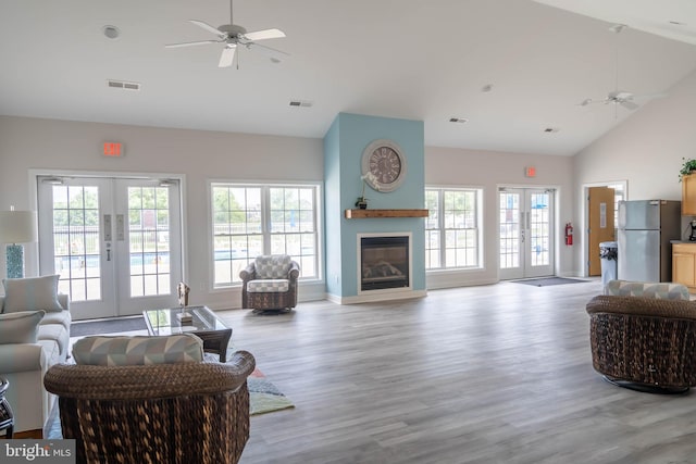 living room featuring french doors, high vaulted ceiling, ceiling fan, and light wood-type flooring