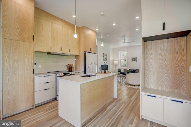 kitchen featuring hanging light fixtures, a kitchen island with sink, light wood-type flooring, and electric range