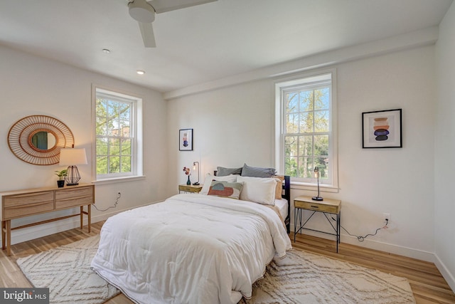 bedroom with multiple windows, ceiling fan, and hardwood / wood-style flooring